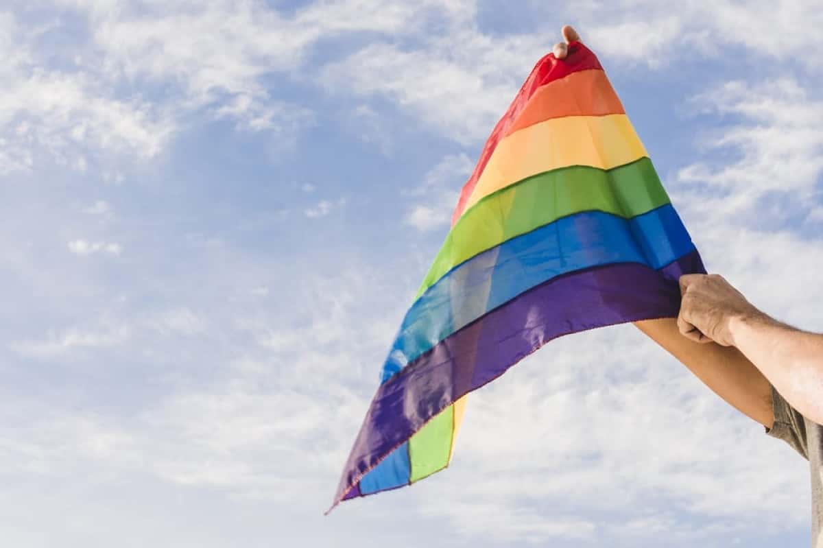 man-with-big-flag-lgbt-colors-blue-sky