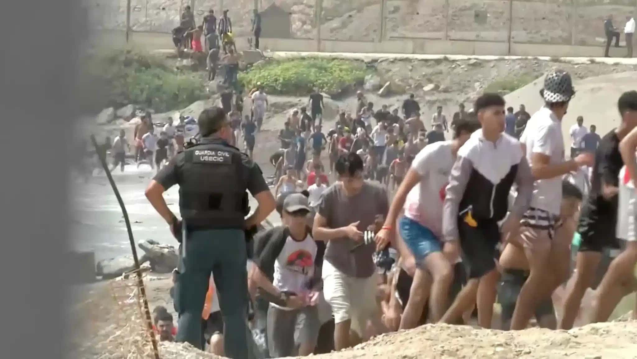 Imigrantes caminham ao lado de um integrante da Guarda Civil após atravessarem a nado a fronteira de Ceuta, na Espanha, vindos do lado de Marrocos