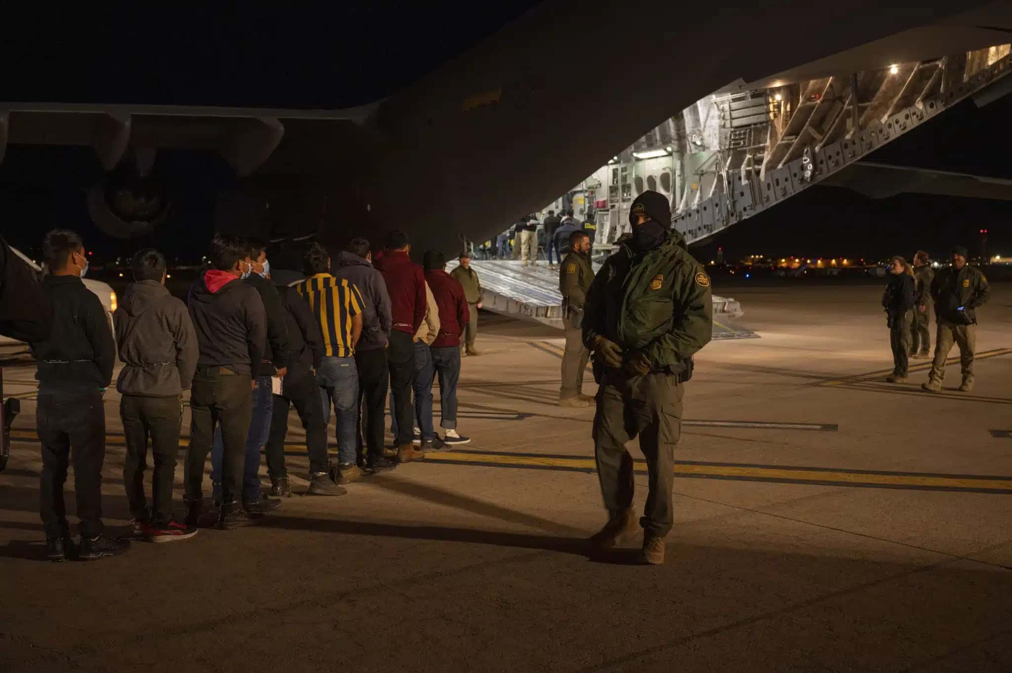 Agentes da Alfândega e Proteção de Fronteiras dos EUA orientam imigrantes a embarcarem em aeronave