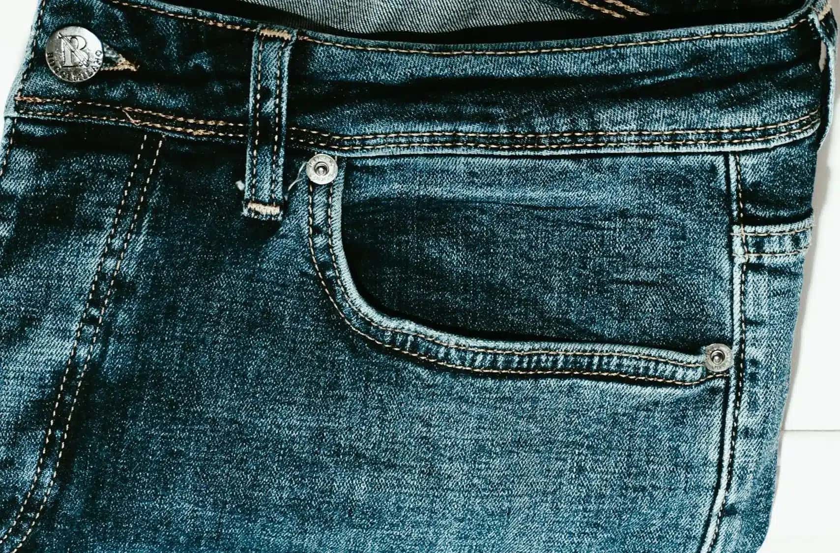 Qual é a função do pino de metal no bolso da calça jeans?