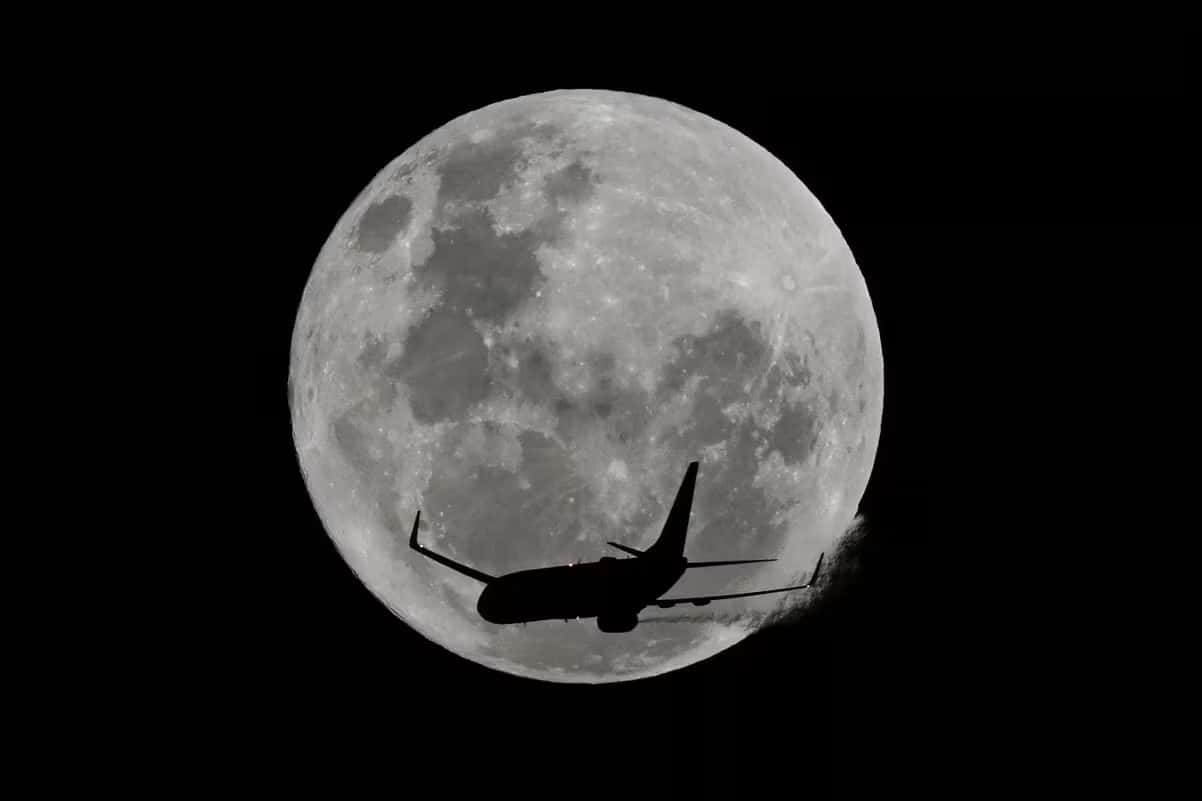 Uma aeronave passa em frente à Lua na Austrália