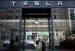 A woman walks past a Tesla store in Washington, DC on March 4, 2019. Tesla is planning to unveil a new electric "crossover" vehicle March 14 which is slightly bigger and more expensive than its most affordable model, according to chief executive Elon Musk. The news comes shortly after Tesla unveiled its lowest-priced Model 3, an electric car designed for the masses, at a base price of $35,000, with deliveries promised within one month. (Photo by Andrew CABALLERO-REYNOLDS / AFP)
