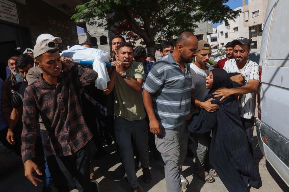 A woman mourns as people carry the body of a Palestinian man who was killed a day earlier in Israeli fire while seeking food aid, during his funeral at Al-Shifa hospital in Gaza City on June 18, 2025. Gaza's civil defence agency said 30 people were killed by Israeli fire in the Palestinian territory on Wednesday, including 11 who were seeking aid. (Photo by Omar AL-QATTAA / AFP)