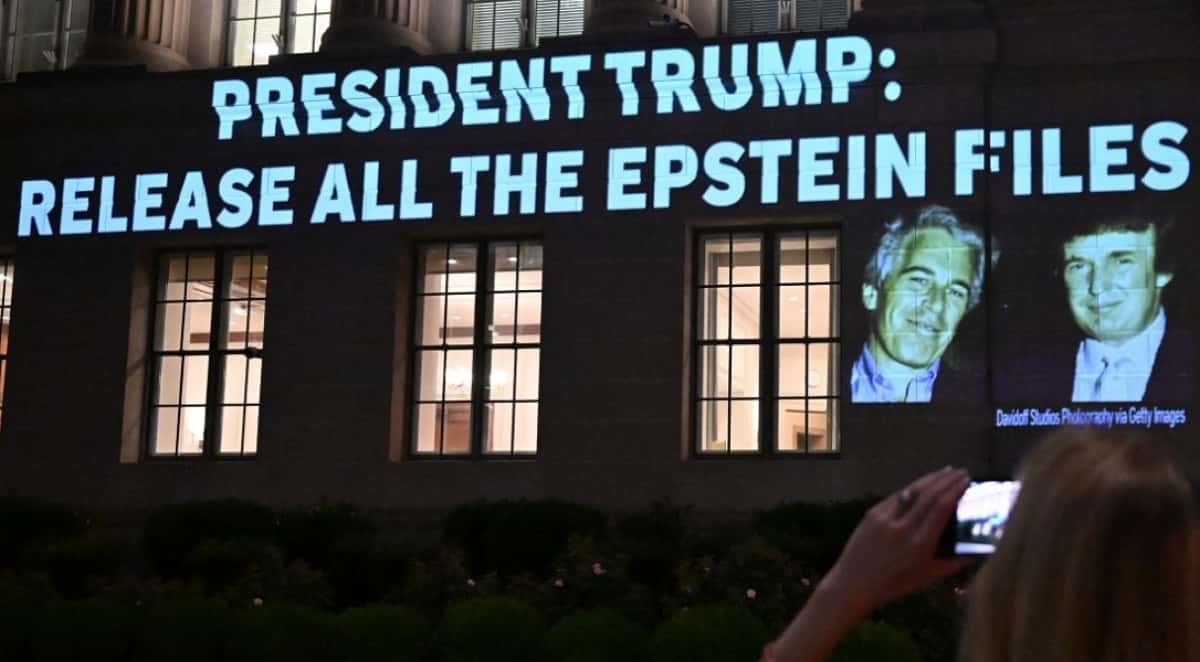 A person takes a photo as a message calling on President Donald Trump to release all files related to Jeffrey Epstein is projected onto the US Chamber of Commerce building across from the White House in Washington, DC, on July 18, 2025. President Donald Trump's administration said it would seek the release of grand jury testimony related to Jeffrey Epstein, as the US president sought to dispel lingering political fallout over his team's handling of the late financier's sex trafficking case. Attorney General Pam Bondi said the Justice Department will ask a court to unseal the grand jury transcripts, as Trump's relationship with Epstein came under the spotlight again over an alleged off-color letter published by the Wall Street Journal. (Photo by Alex WROBLEWSKI / AFP)