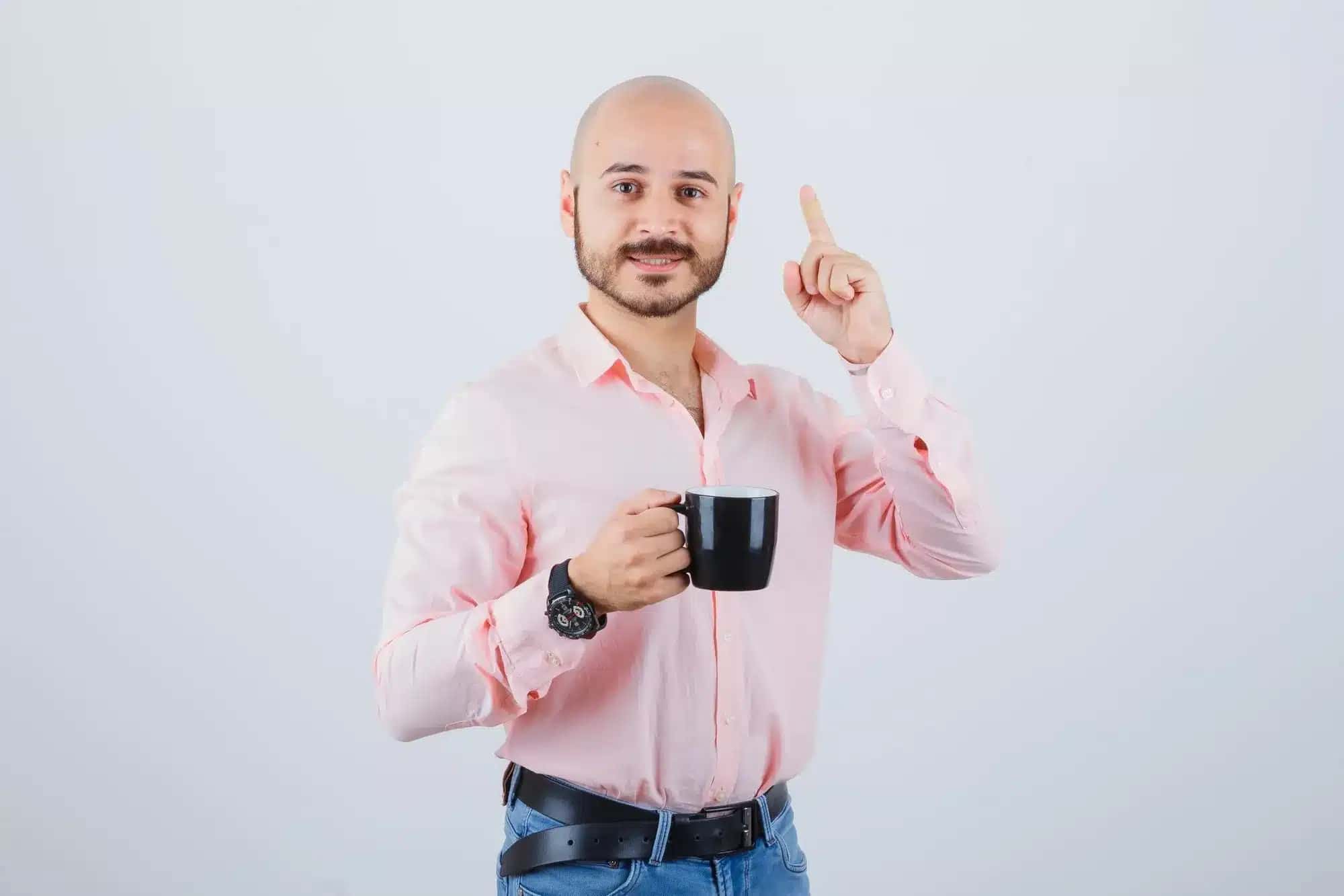 homem-calvo-com-xicara-de-cafe-e-apontando-para-cabeca