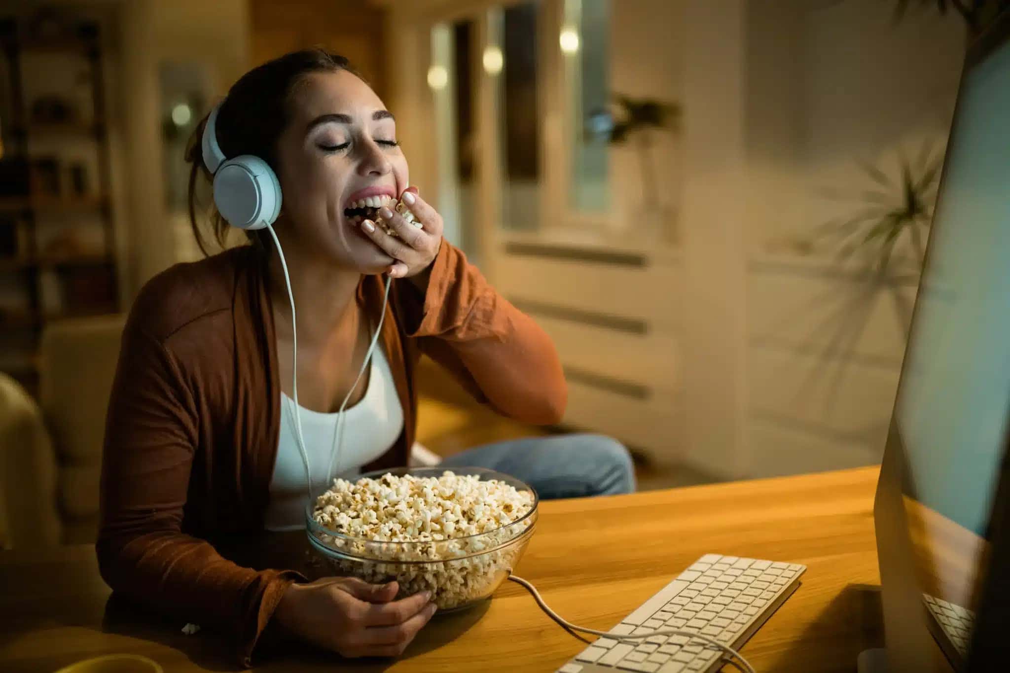 jovem-de-olhos-fechados-desfrutando-enquanto-come-pipoca-durante-noite-de-cinema-em-casa-1