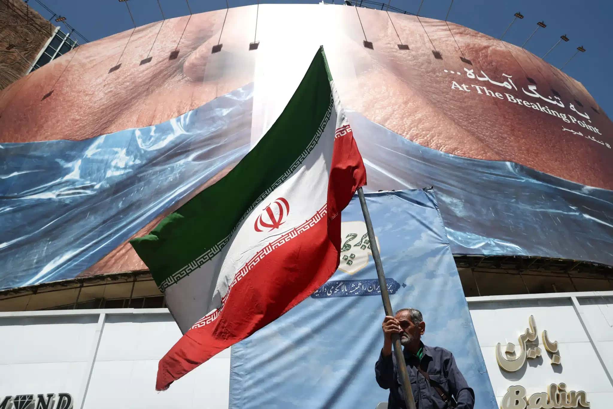 Homem-segura-bandeira-iraniana-perto-de-outdoor-anti-EUA-representando-o-presidente-dos-EUA-Donald-Trump-e-o-Estreito-de-Ormuz-em-Teera-Ira-em-30-de-maio-de-2026-4