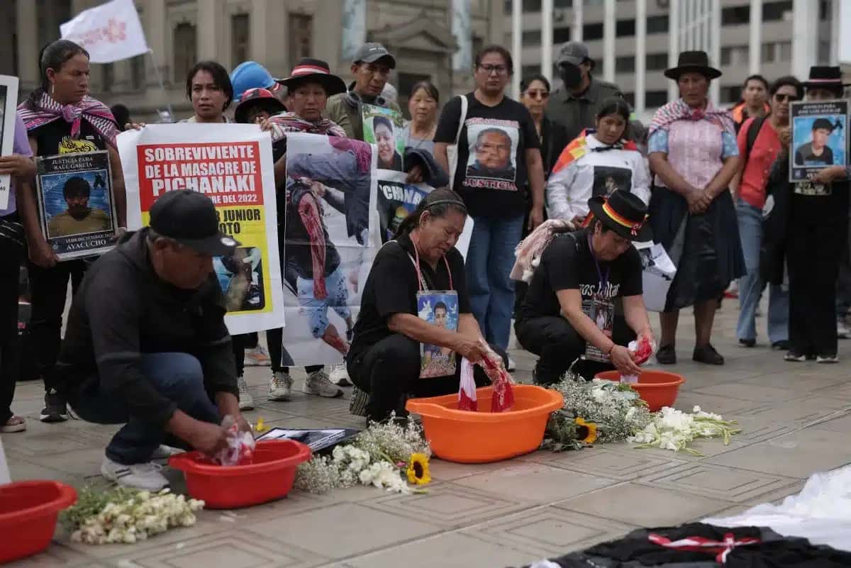 Parentes de vítimas de crimes supostamente cometidos pelo Estado peruano lavam bandeiras nacionais durante protesto do lado de fora do Palácio da Justiça, em Lima, em 28 de julho de 2025.