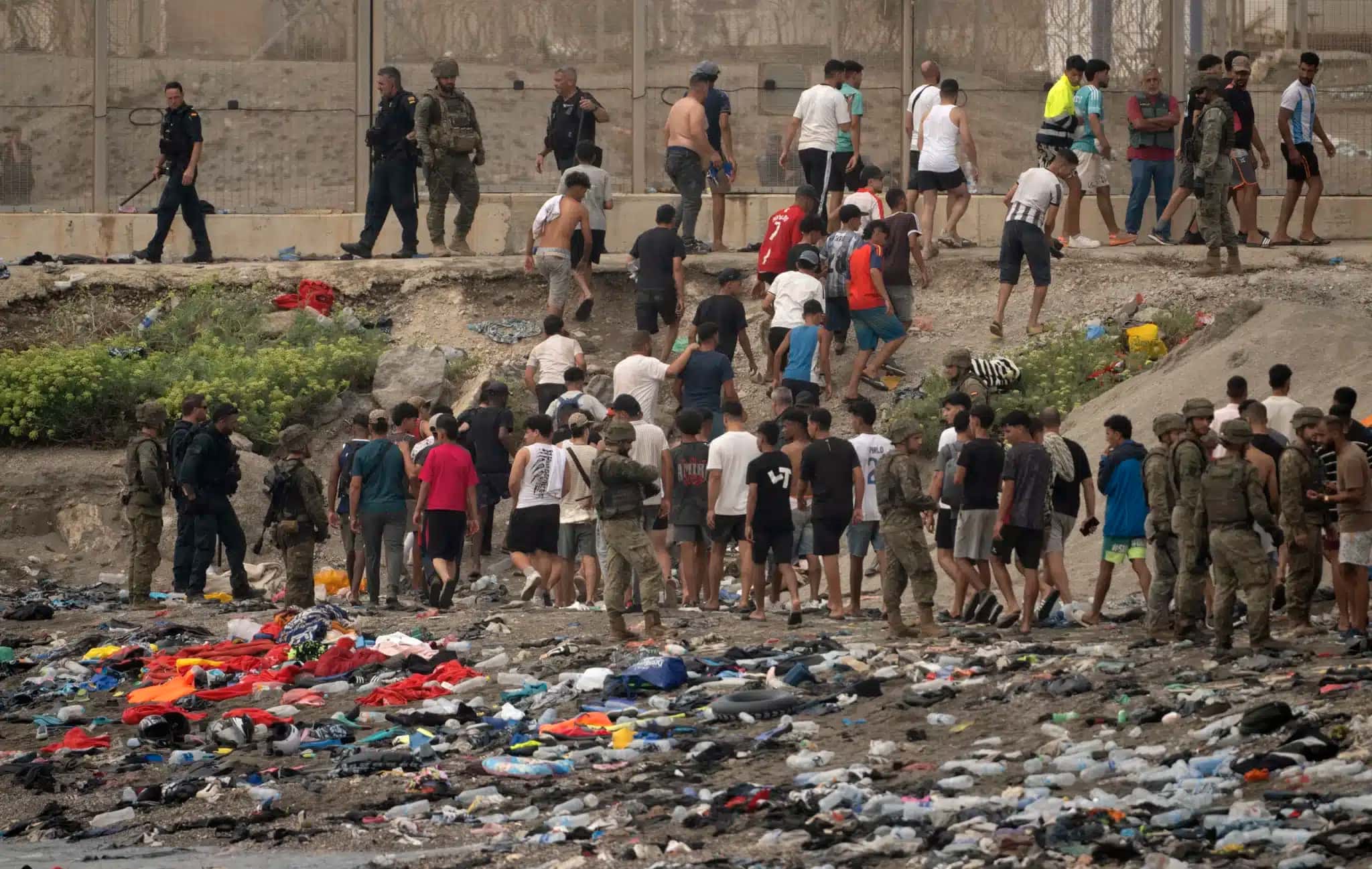 Soldados controlam enquanto imigrantes atravessam de volta ao Marrocos depois de cruzarem a fronteira para entrar na cidade espanhola de Ceuta, no Norte da África. 31/07/2026