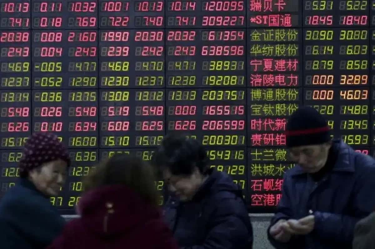 Investidores em frente a quadro eletrônico mostrando informações sobre o mercado acionário, em Xangai, China