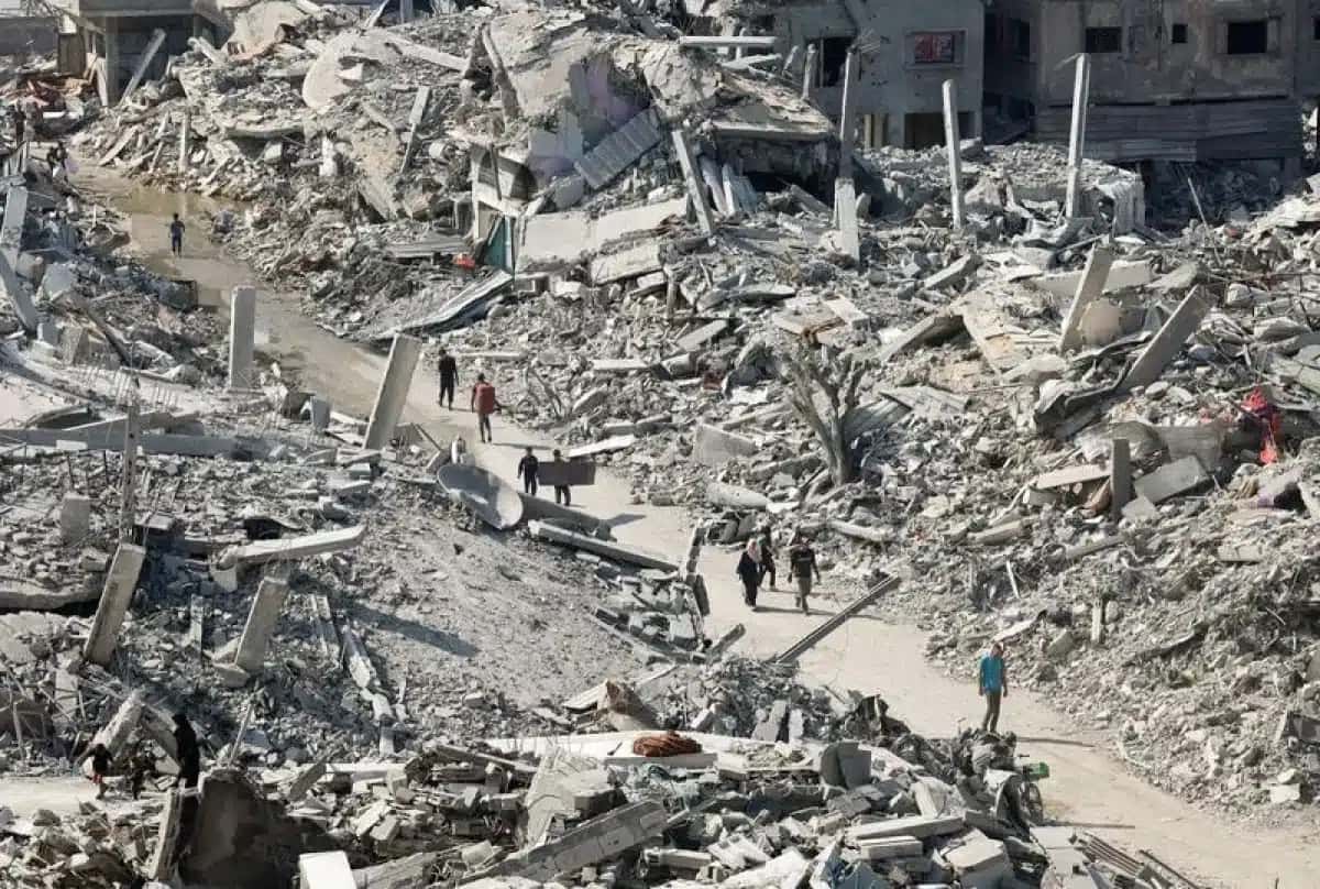 Palestinianos passam pelos escombros de edifícios destruídos, no meio de um cessar-fogo entre Israel e o Hamas, na cidade de Gaza