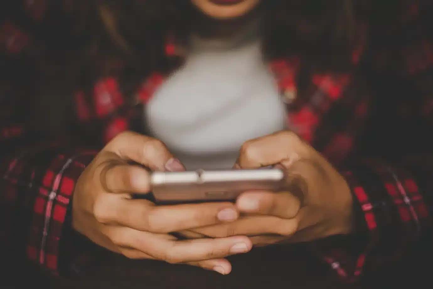 Close up of woman's hands holding smartphone. Hipster girl with her mobile phone at cafe. Vintage filter effect.