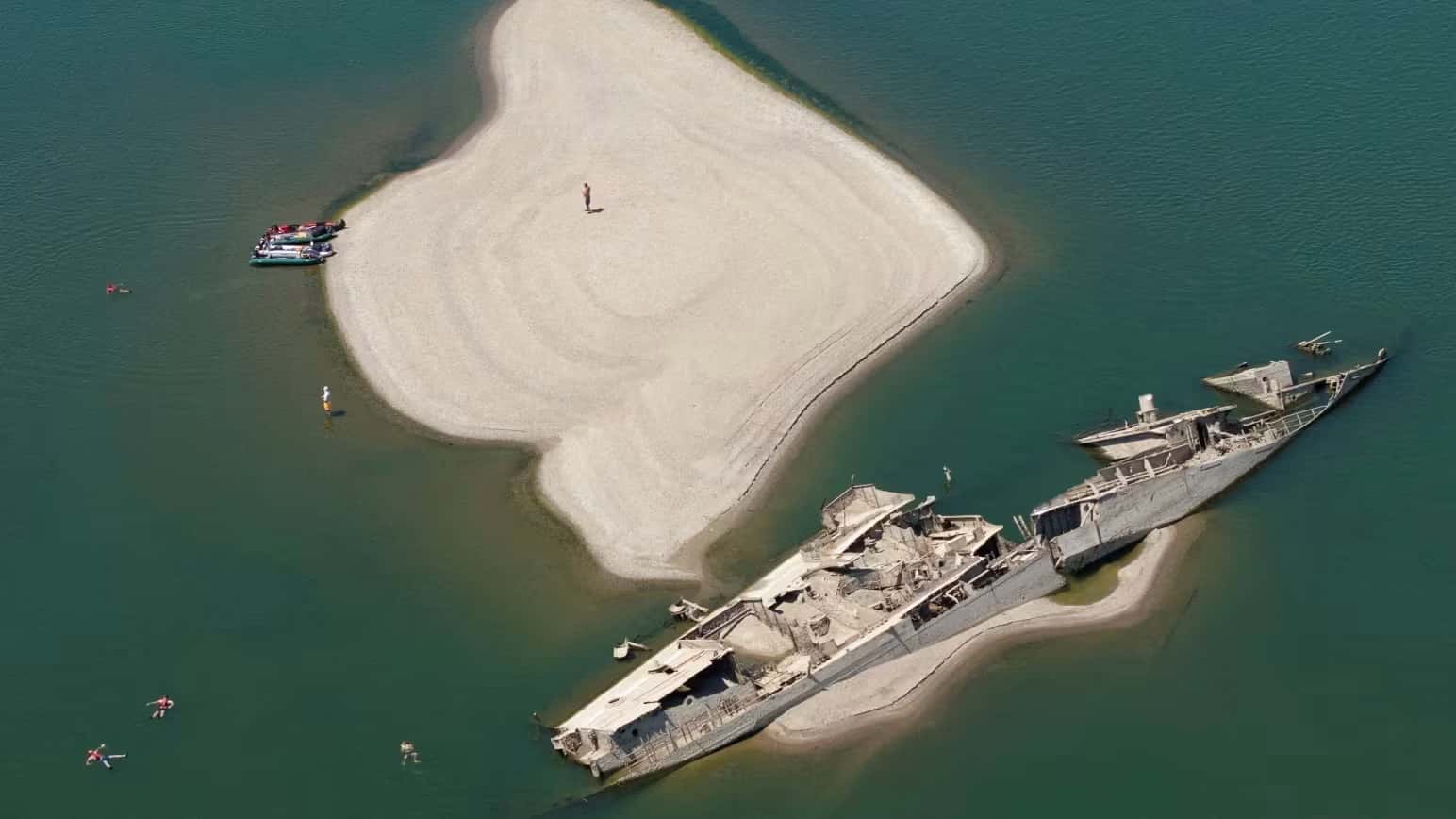Pessoas nadando perto de um navio de guerra alemão afundado da Segunda Guerra Mundial, exposto devido aos baixos níveis do rio Danúbio, em Prahovo, Sérvia, 30 de julho de 2026