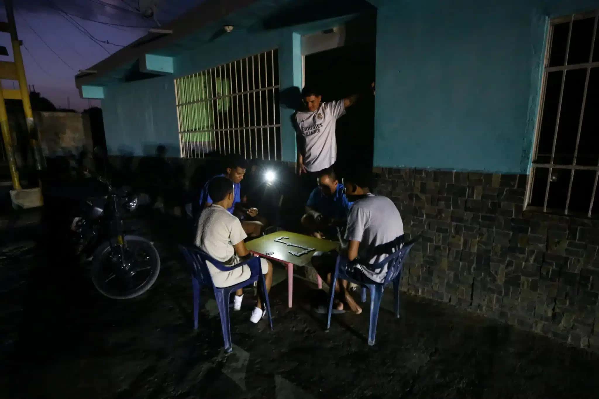 Pessoas jogam dominó com luz de celular durante apagão em Valência, na Venezuela