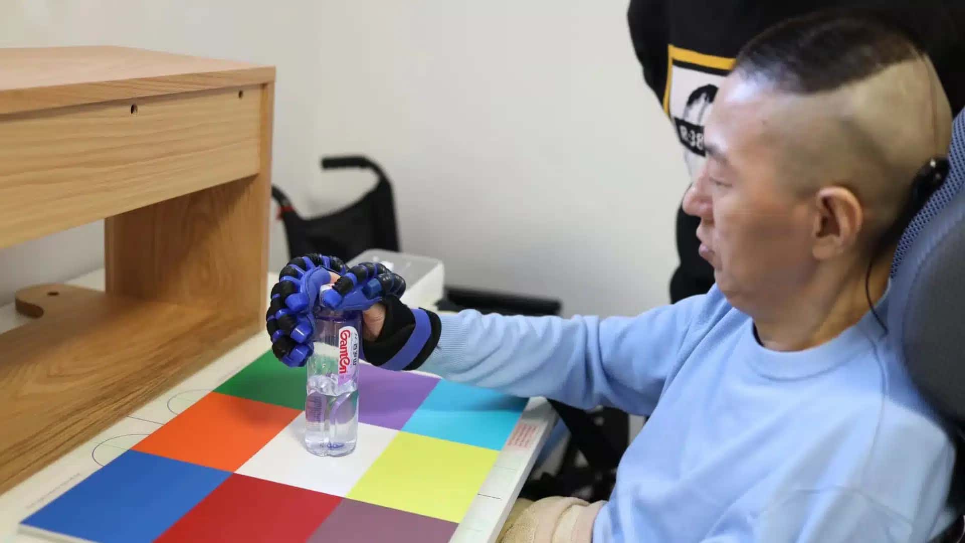 O paciente segura uma garrafa usando o sistema BCI sem fio NEO e uma prótese de mão.