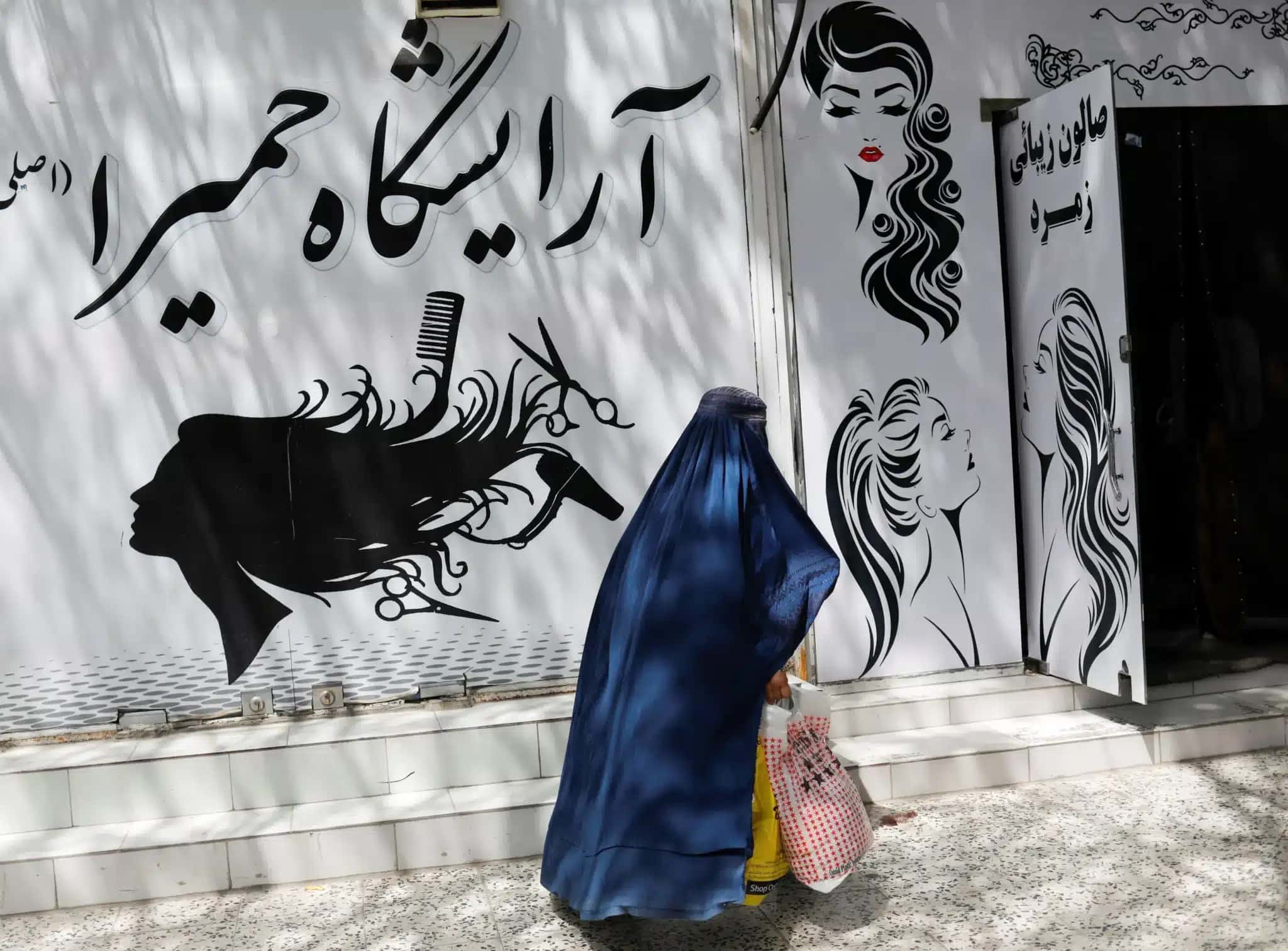 Mulher afegã passa por um salão de beleza em Cabul 6 de julho de 2023 REUTERS/Ali Khara