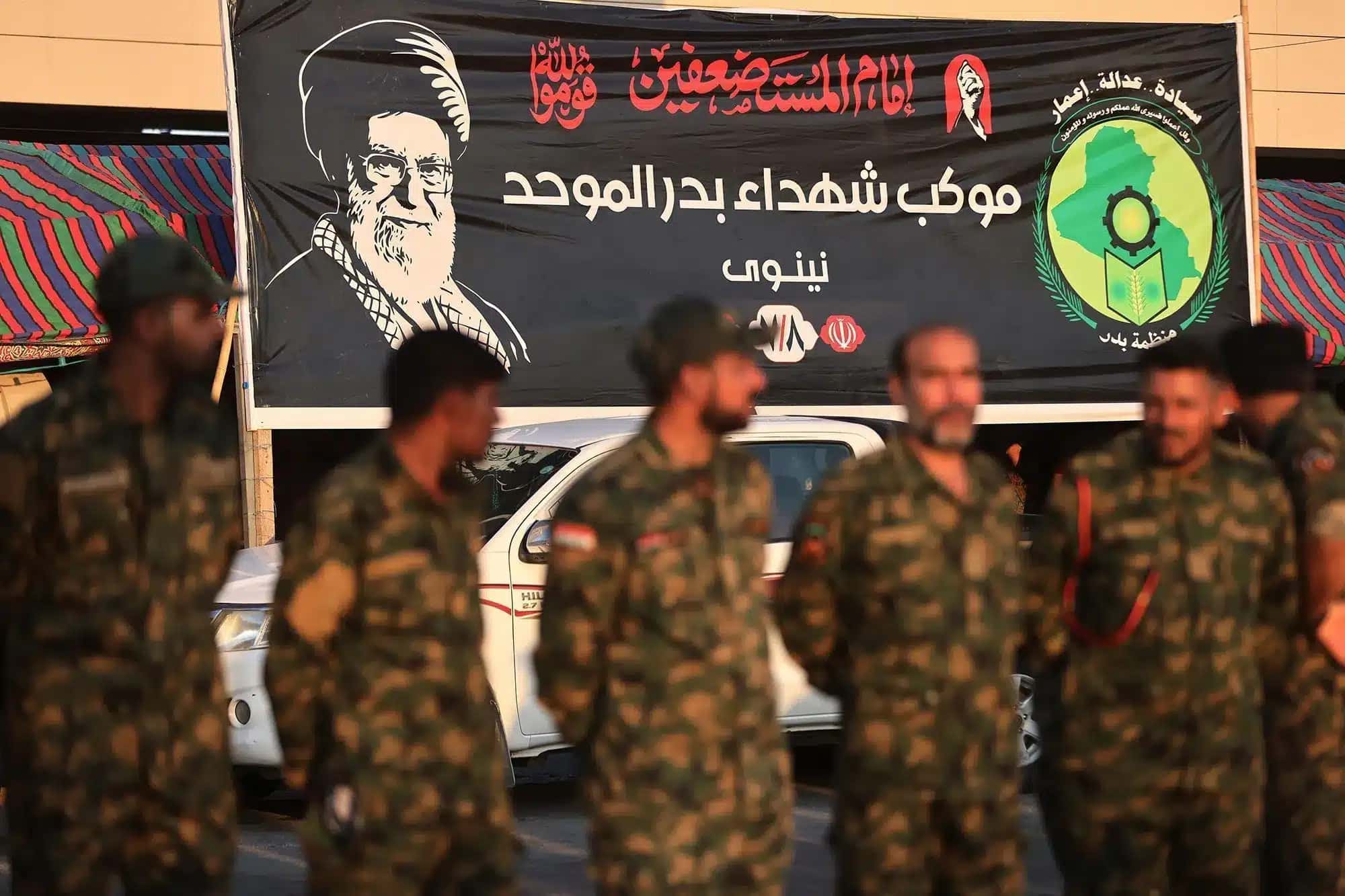 Membros das Forças de Mobilização Popular do Iraque estão perto de um retrato do falecido líder supremo do Irã, Ali Khamenei, no santuário do Imã Hussein, na véspera de suas cerimônias fúnebres na cidade sagrada iraquiana de Karbala, em 7 de julho