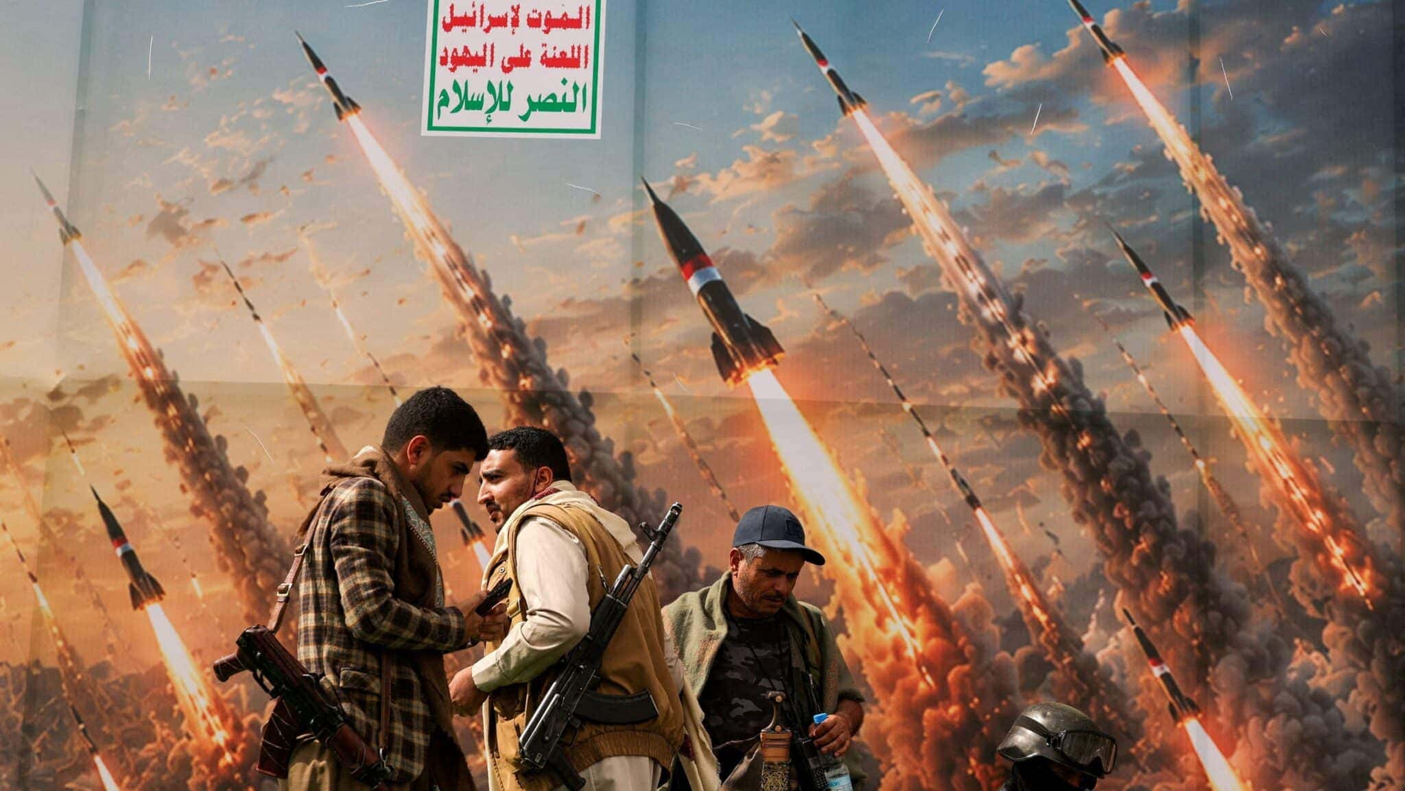 Houthis diante de banner que retrata mísseis em manifestação contra a Arábia Saudita, em Sanaa, no Iêmen