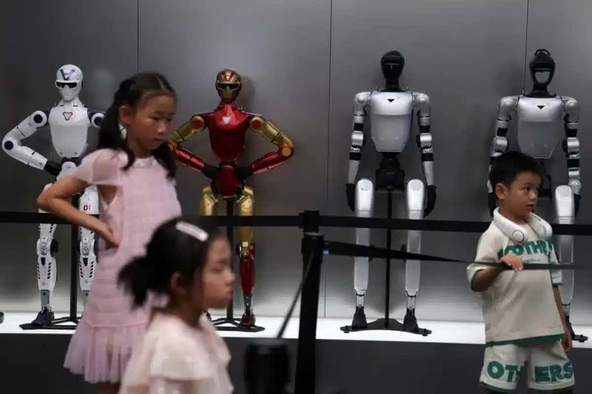 Crianças ao lado dos robôs humanóides da Unitree em exposição em uma loja da Unitree em Pequim