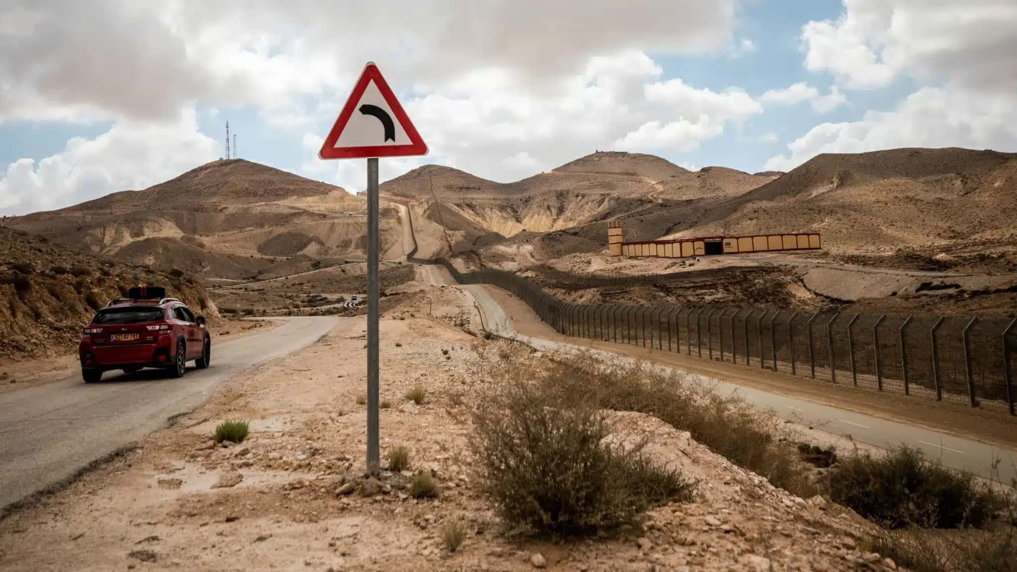 Um carro israelense circula em estrada monitorada por posto de controle militar egípcio na fronteira com Israel, visto do sul de Israel.