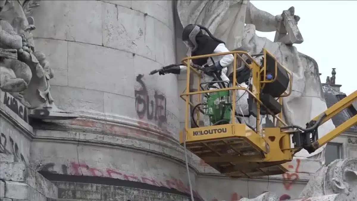 Trabalhadores removendo pichações do monumento na Place de la République, em Paris, após protestos de estudantes.