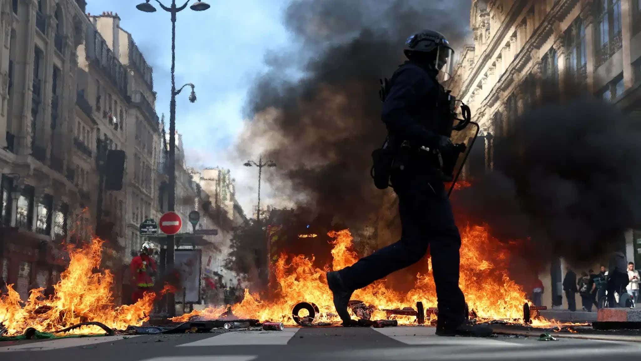 Polícia de choque da França passa por objetos em chamas em meio a confrontos com manifestantes em Paris, como parte dos protestos em todo o país contra o custo de vida e o aumento dos preços dos combustíveis.